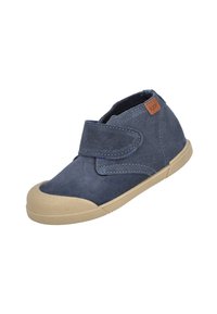 Zapato de charol azul para niño pequeño, con suela y puntera de goma beige, que presenta una correa de Velcro y una etiqueta de marca en el lateral.
