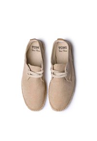 Scarpe beige in tela con design a lacci, caratterizzate da dettagli cuciti, punta rotonda e suola testurizzata. Marchio visibile all'interno.