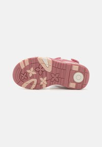 Pink rubber sole with embossed flower pattern and white accents. Features textured grip lines and circular logo detail. Lightweight design.