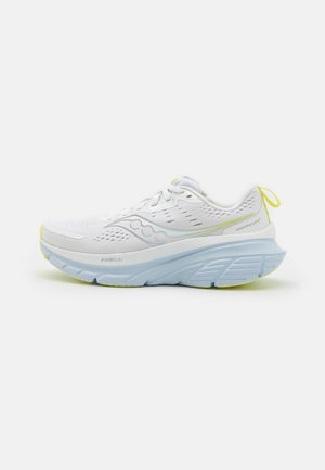 Chaussure de course blanche avec une tige en mesh, présentant des accents bleu clair et une semelle épaisse. Détails jaunes remarquables sur la semelle et l'onglet du talon.