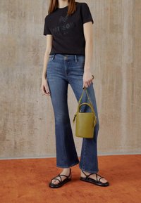 Musta lyhythihainen t-paita, jossa Missonin logo, siniset liehuvat farkut, mustat sandaalit remmeillä ja pieni keltainen nahkalaukku, jossa on kahva.