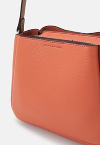 Borsa a tracolla in pelle arancione con texture, dalla forma strutturata, dotata di una tracolla removibile e di una delicata cucitura lungo i bordi.
