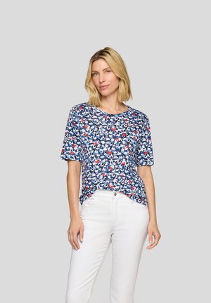 Floral short-sleeve top in navy with white and red accents; round neckline, relaxed fit, paired with white pants, smooth fabric texture.