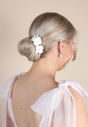 Accessorio per bun di capelli bianchi con design floreale che presenta tre fiori, arricchiti con piccole perline. I capelli sono biondi chiari, di texture liscia.