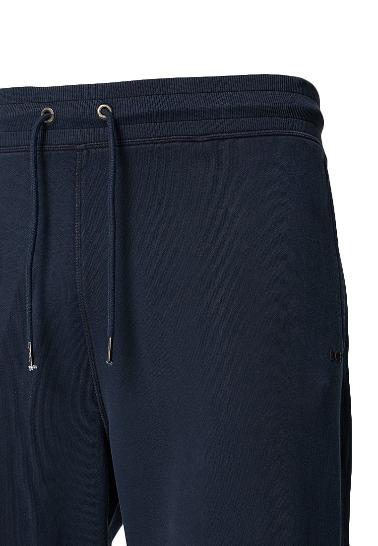 Granatowe spodnie dresowe z elastycznym pasem, sznurkiem ściągającym i złotymi akcentami. Posiadają gładką teksturę i boczne kieszenie.