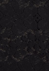 Svart spetstyg med en texturerad mönstring med blommotiv och öppna vävningar. Materialet har ett mjukt, ömtåligt utseende.