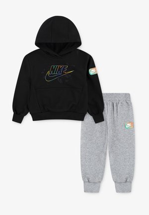Čierna mikina Nike s farebným logom a zodpovedajúce šedé teplákové nohavice s malou nášivkou loga Nike na ľavom stehne a pravom rukáve.