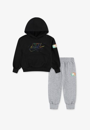 Fato de treino preto da Nike com um logótipo colorido e calças de fato de treino cinzentas a condizer, apresentando um pequeno emblema da Nike na perna esquerda e nas mangas direitas.
