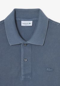 Niebieska koszulka polo z teksturowanej bawełny, z ribbowanym kołnierzykiem, zapięciem na dwa guziki i haftowanym logo na piersi.