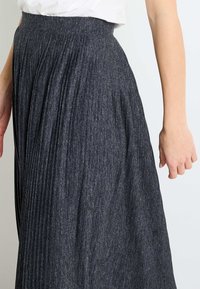 Falda gris plisada hecha de tejido texturizado con una cintura ajustada, que muestra pliegues verticales y un acabado suave.
