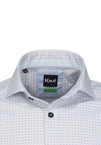 Camicia button-up azzurro chiaro con un motivo geometrico, colletto a contrasto, tessuto morbido e un bottone scuro. L'etichetta del marchio è visibile all'interno.
