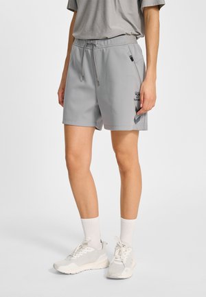 Persoon draagt lichtgrijze sportkorte broek met trekkoord, witte sokken en witte sportschoenen tegen een effen achtergrond.