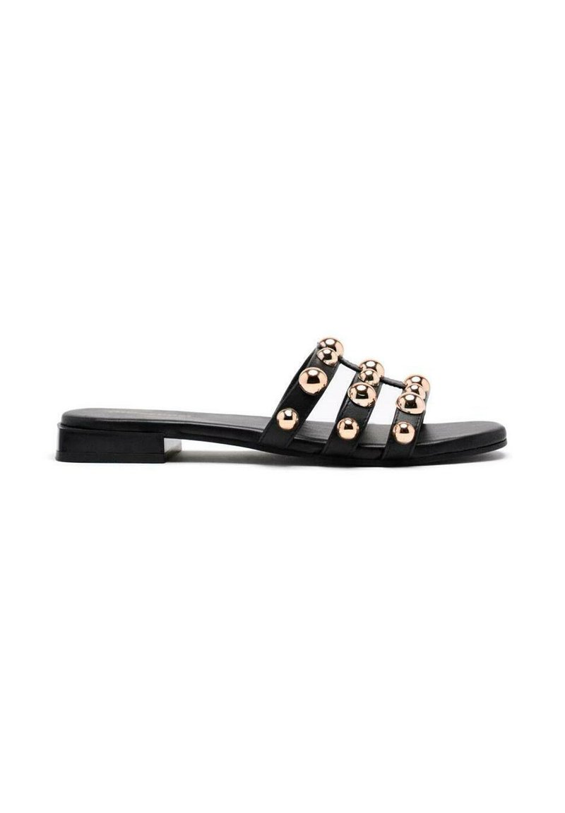 Sandales plates noires avec trois brides, dotées de sphères métalliques dorées comme accents, à la texture lisse et avec un petit talon rectangulaire.