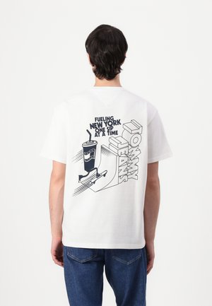 Witte katoenen t-shirt met een grafisch ontwerp op de achterkant, inclusief tekst en illustraties van een drankje en een skateboard. Klassieke ronde halsstijl.
