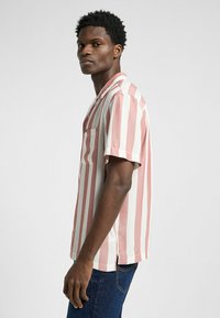Kurze Ärmel Bluse mit kräftigen weißen und sanften rosa vertikalen Streifen, einer Brusttasche und einem entspannten Kragendesign.