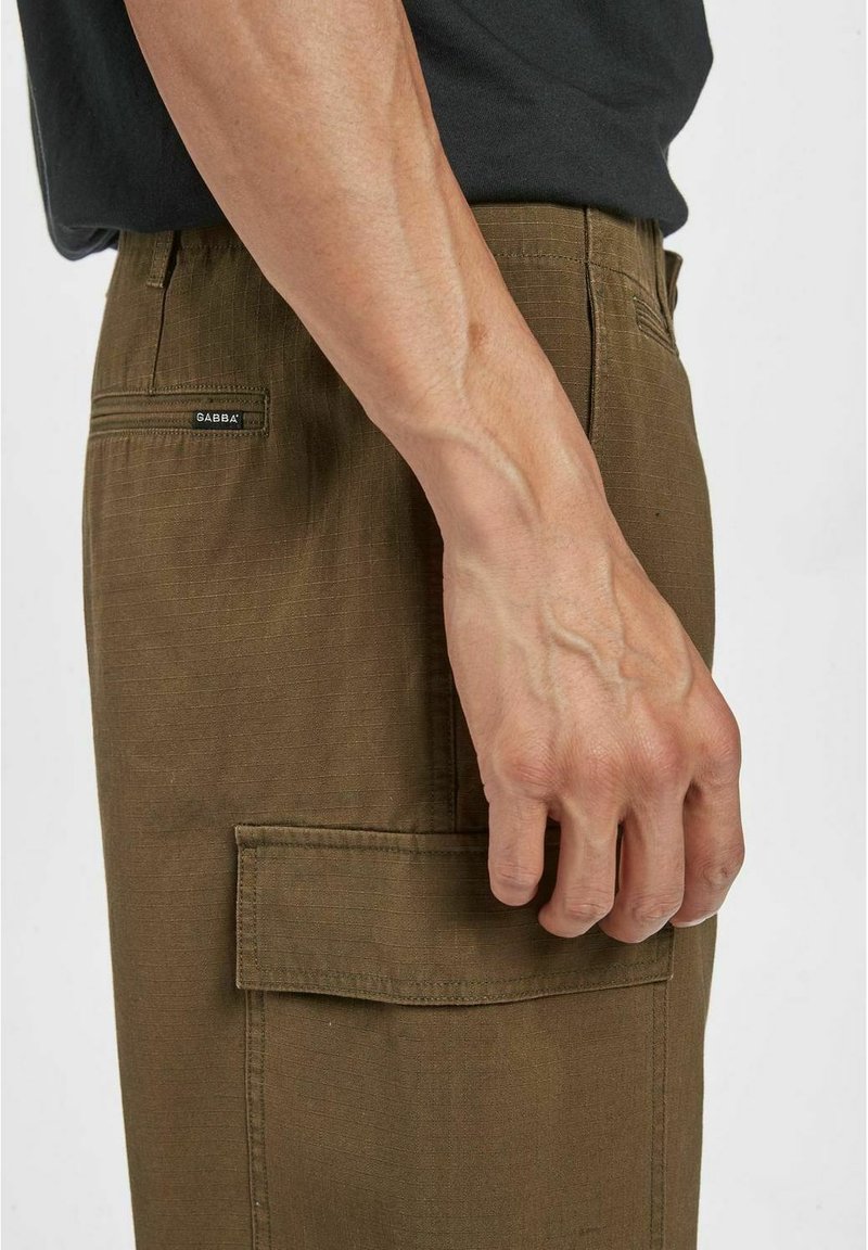 Pantaloni cargo marroni con una trama testurizzata, dotati di una tasca laterale e di un'etichetta. La cintura include un passante per la cintura, evidenziando un design a vestibilità slim.