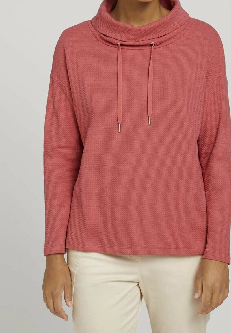 Bluza z mieszaniny bawełny z golfem w stonowanym różowym kolorze, z troczkami, fakturowaną powierzchnią i długimi rękawami, zestawiona z jasnobeżowymi spodniami.