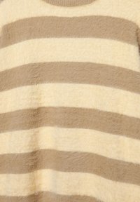 Pörröinen neulepaita, jossa on vaalean kerma- ja vaaleanruskeita vaakaraitoja. Pyöreä kaula-aukko, pehmeä rakenne ja näkyvät kuidut luovat kotoisan ilmeen.