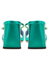 Sandales à talons hauts métalliques verts avec un épais talon bloc, des fines lanières et une texture lisse et brillante. Design à bout légèrement arrondi.