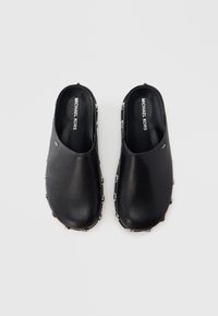 Black leather clogs featuring a smooth surface and silver-toned hardware accents around the edge. Inside displays the "MICHAEL KORS" branding.