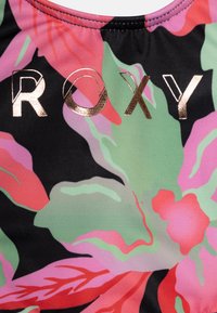 Melnā auduma ar spilgtu ziedu rakstu rozā, zaļā un sarkanā krāsā, ar zeltītu "ROXY" logotipu izcili redzamā vietā.