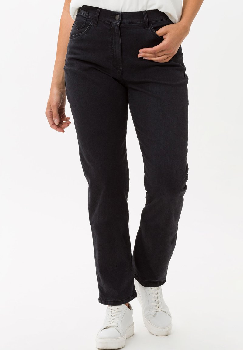 Jeans in denim blu scuro con taglio dritto, dotati di zip, cinque tasche e dettagli di cucitura frontale sottili. Abbinati a sneakers bianche.