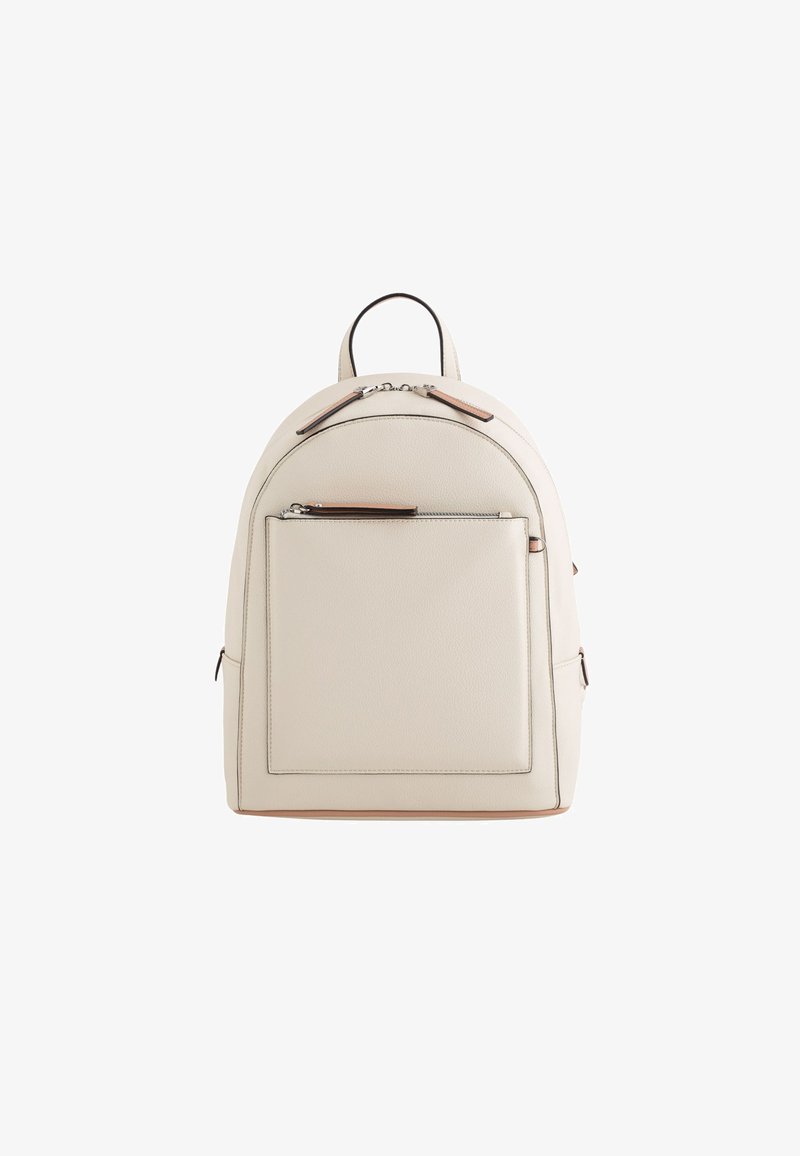 Beige leather backpack with rounded shape, top handle, front zip pocket, and brown accents on zippers and edges. Smooth texture.