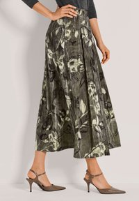 Midi-rok met plooi en bloemenpatroon in tinten groen en zwart, gecombineerd met bruine slingback hakken met spitse neus. Zachte stoftextuur.