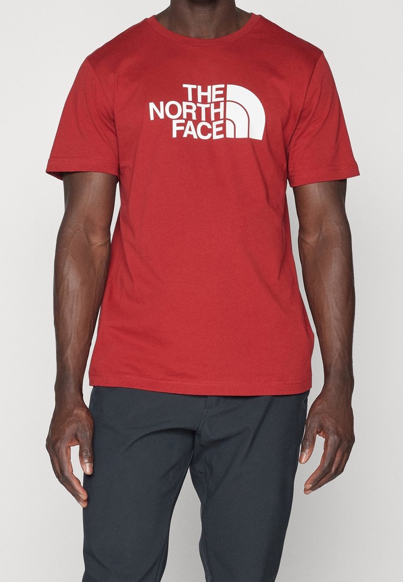 Red cotton t-shirt with short sleeves, featuring a large white "THE NORTH FACE" logo in a curved design across the front.