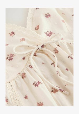 Tissu de robe couleur crème avec petit imprimé floral violet, bordure en dentelle et nœud noué à la taille.