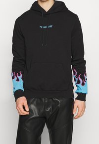 Sweat à capuche noir avec une poche avant, arborant des motifs de flammes bleues sur les manches et un texte bleu sur la poitrine. Tissu en coton doux.