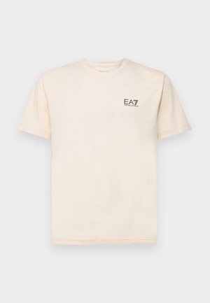 T-shirt in cotone color crema con maniche corte, collo rotondo e piccolo logo EA7 nero sul lato sinistro del petto. Texture liscia, vestibilità casual.