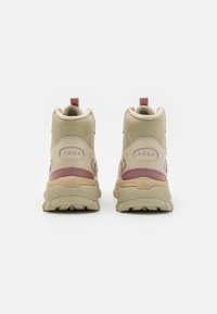 Beige hohe Sneaker mit pinken Akzenten, einer strukturierten Ferse, gepolstertem Schaft und Schnürsenkeln mit einer strapazierfähigen Gummisohle. ARKK-Logo sichtbar.