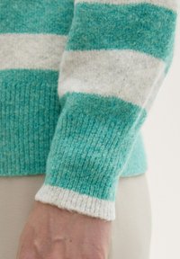 Türkis-weißer gestreifter Strickpullover mit strukturiertem Stoff, gerippten Bündchen und einer körpernahen Passform.