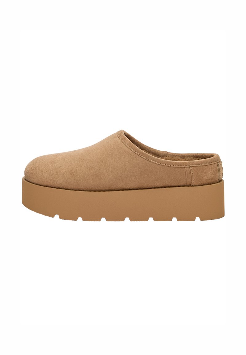 Barna velúr slip-on cipő lekerekített orral és vastag, fogazott talpával. Minimalista varrással és látható hardver nélkül rendelkezik.
