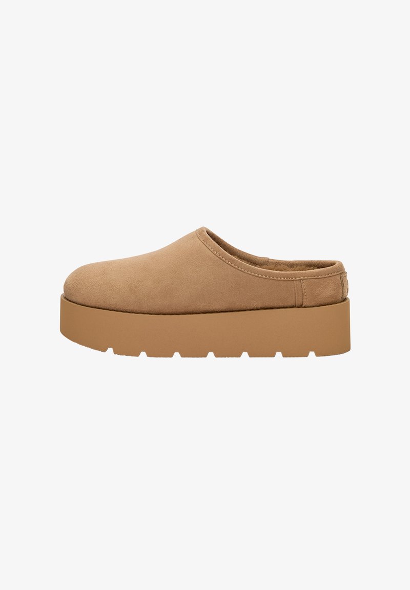 Chaussure slip-on en daim taupe avec un bout rond et une semelle épaisse crantée. Présente une couture minimale et aucun matériel visible.