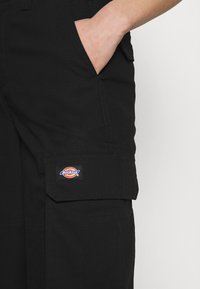 Zwarte cargobroek van stevig materiaal, met een zijzak en een kleurrijke Dickies logo patch op de pijp gestikt.