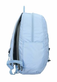 Mochila azul claro con un exterior de tela suave, panel trasero acolchado, correas ajustables y un bolsillo lateral. Presenta cremalleras y detalles de herrajes.