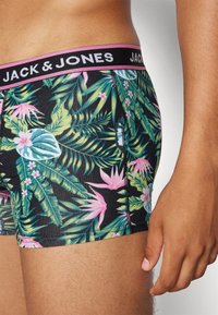 Schwarze Boxershorts mit bunten Mustern von tropischen Blättern und Blumen, ausgestattet mit einem schwarzen Bund, der "JACK & JONES" in weißem Text zeigt.