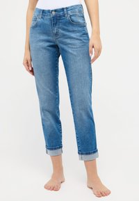 Hellblaue Jeans aus Denim mit einer lässigen Passform, featuring einen vorderen Knopfverschluss, fünf Taschen und hochgekrempelten Bündchen an den Knöcheln.