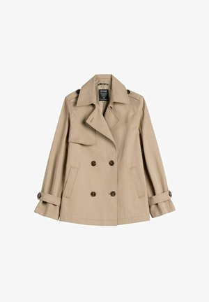 Beżowy dwurzędowy płaszcz trencz z szerokimi klapami, zapinanymi na guziki naramiennikami, paskami na mankietach oraz dwoma przednimi kieszeniami, przedstawiony na płasko.