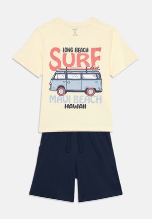 Kreemjas T-särk sinise kaubiku ja lainelaudade graafikuga, tumesinised lühikesed püksid, laste vabaaja suvine komplekt.