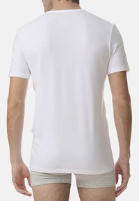 Biała bawełniana koszulka z krótkim rękawem i okrągłym dekoltem, widoczna z tyłu. Materiał wygląda na gładki i lekki.