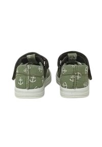 Scarpe in tela verde con motivi bianchi a forma di ancora, dotate di una cinturino in pelle scura e suola in gomma bianca. La vista posteriore mostra dettagli di cucitura.