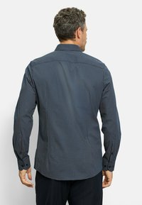 Langarm-Navy-Hemd mit geometrischem weißen Muster, geknöpften Manschetten und klassischem Kragen. Glattes Gewebe mit taillierter Passform.