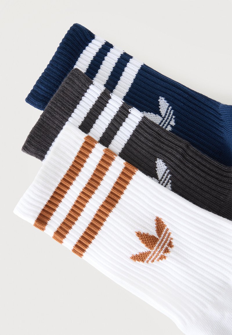 Three ribbed socks in navy, black, and white, each with three stripes and an Adidas Trefoil logo in contrasting colors near the top.
