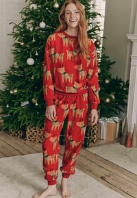 Rode loungewear set met rendierpatroon; sweatshirt met lange mouwen, elastische manchetten en bijpassende broek met elastische tailleband.