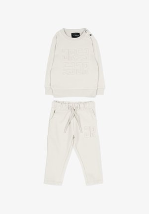 Crèmekleurige kindertrui met geometrisch reliëf design en bijpassende broek met trekkoord, zijzakken en elastische tailleband.
