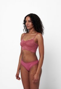 Spitzen-Bralette und passende Unterwäsche in staubigem Rosenrot mit gewelltem Saum. Weicher Stoff, verstellbare Träger und schlichtes Design.