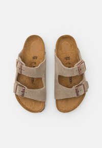 Μπεζ σουέτ σανδάλια με δύο ρυθμιζόμενους δακτυλίους, φελλώδη πέλματα και επίπεδη καουτσούκ σόλα. Σχεδιασμένα για άνεση και εύκολη χρήση.